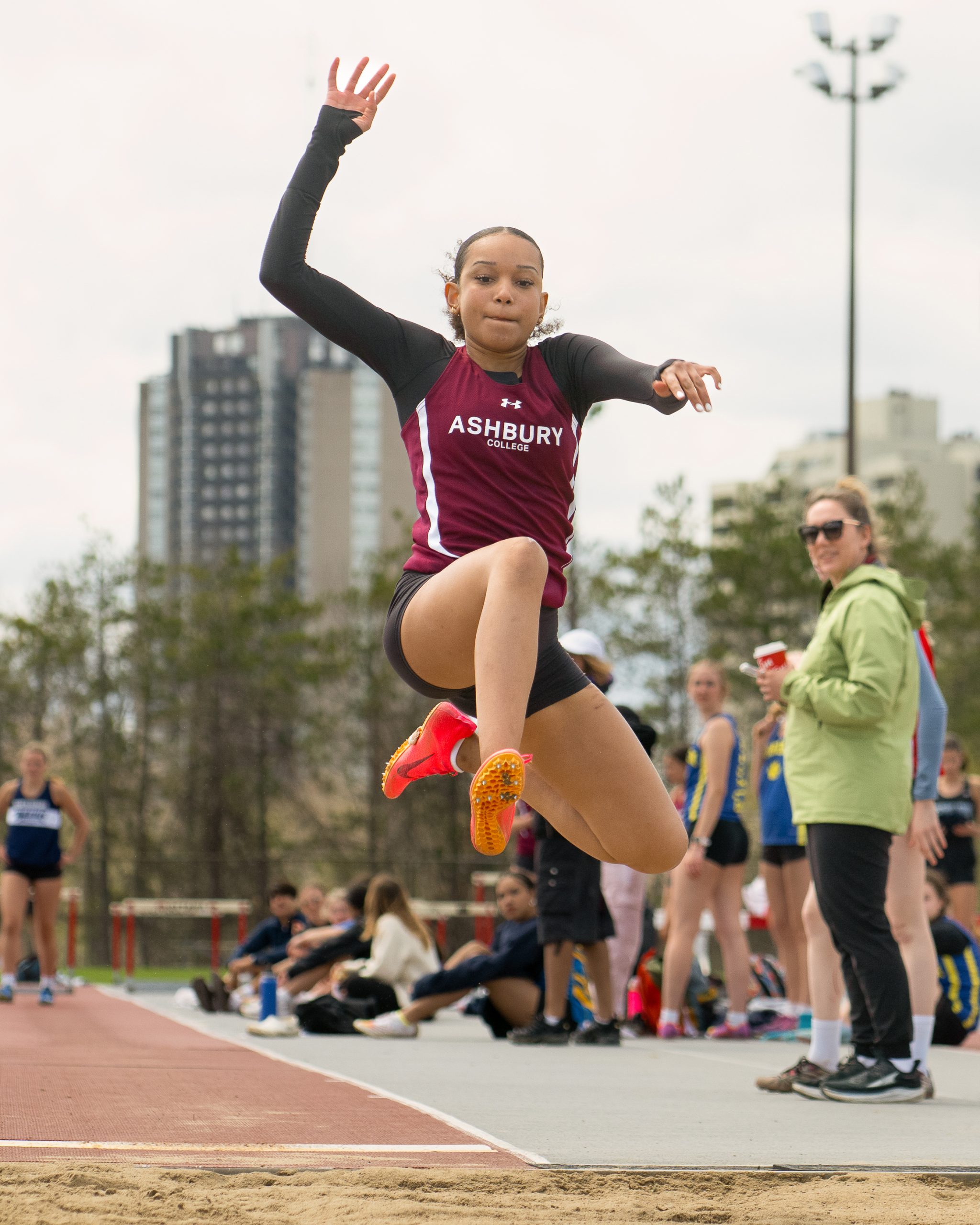 Young woman leaping in the air across a long jump pit