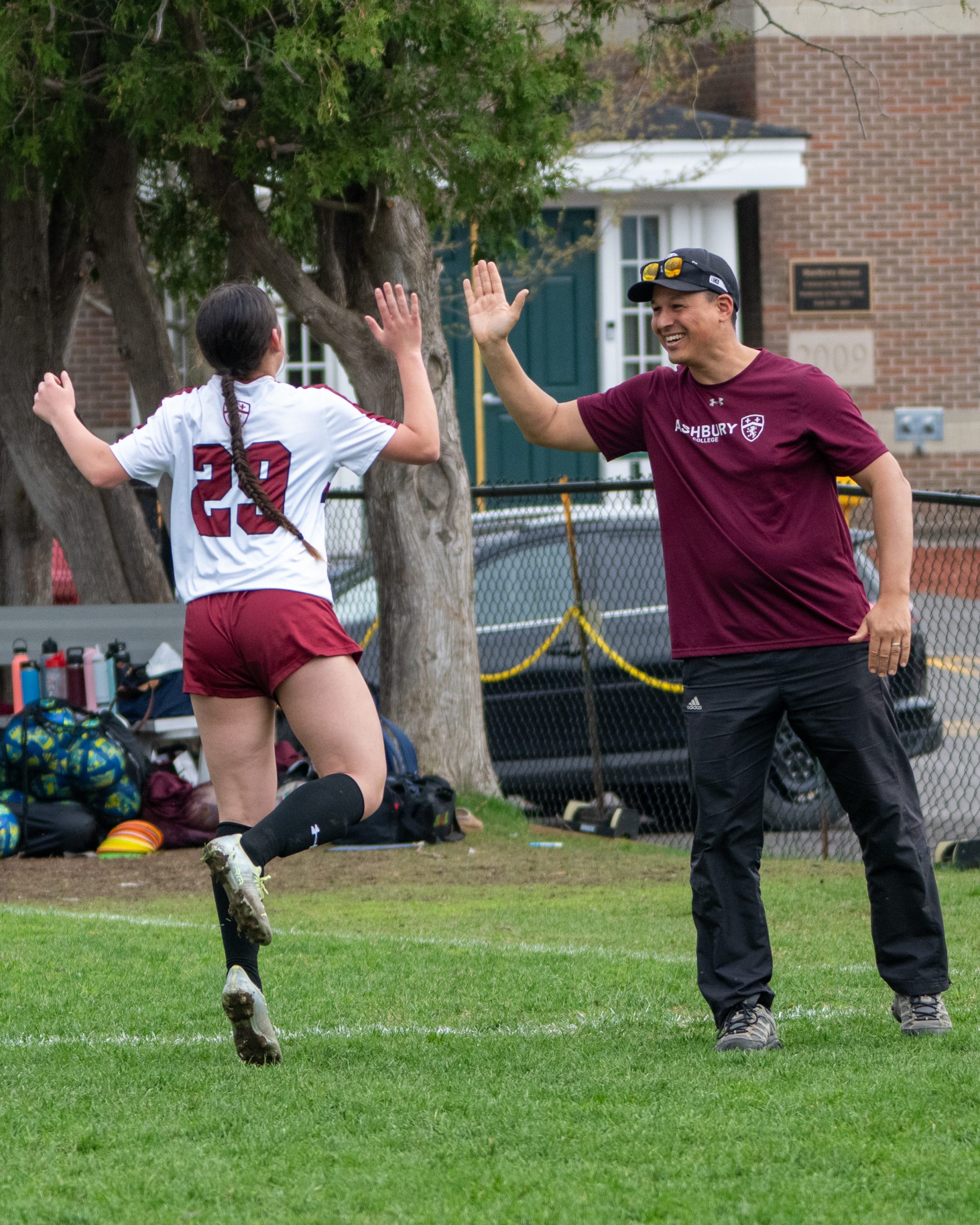 Young woman in a soccer uniform high-fiving a coach