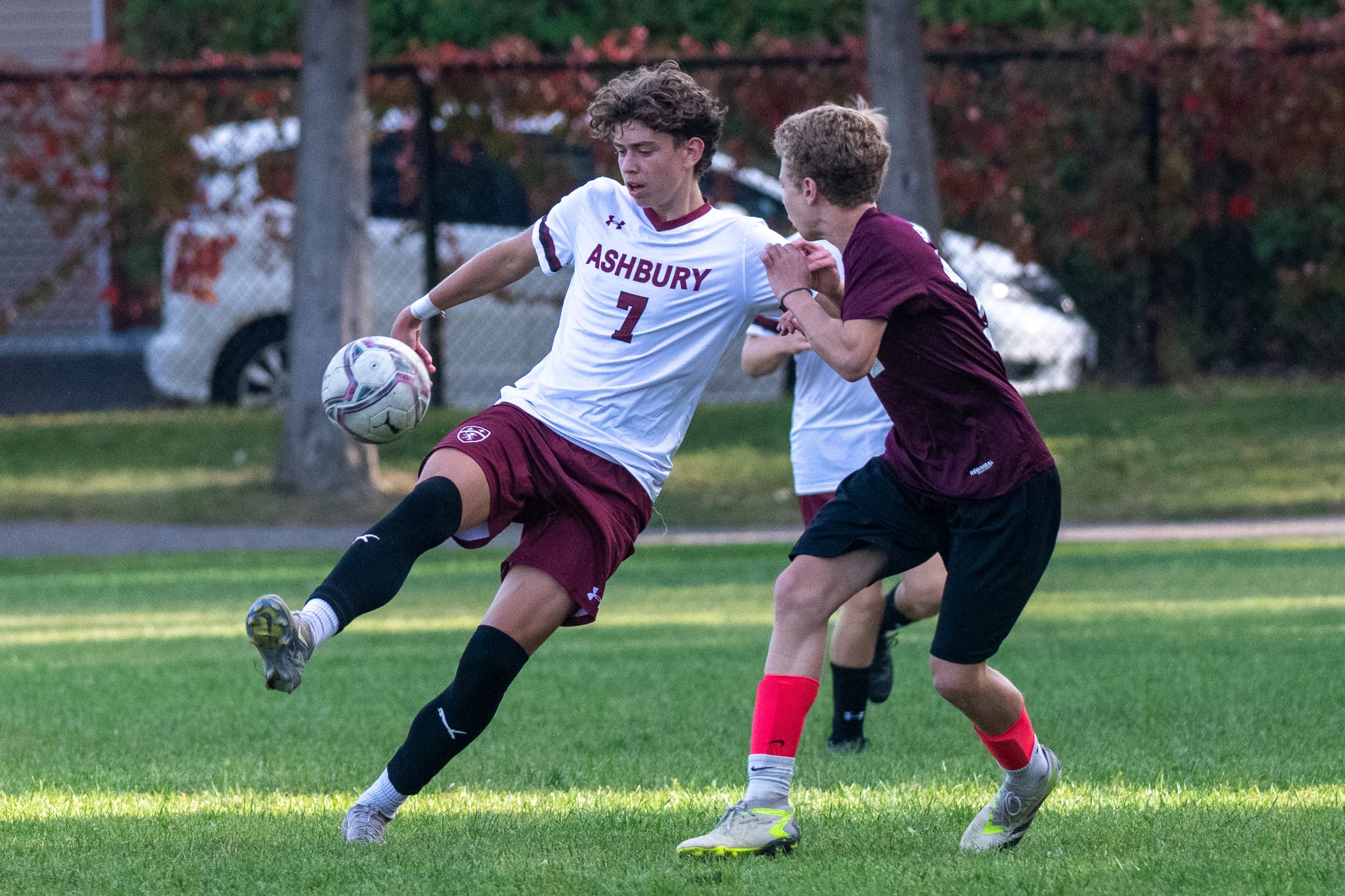 2 men playing soccer competing for the ball on the field