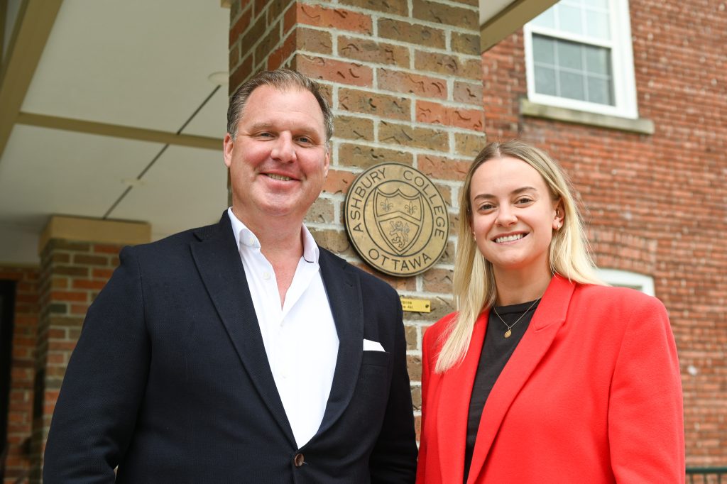 An older man in a suit is smiling next to a middle-aged woman 