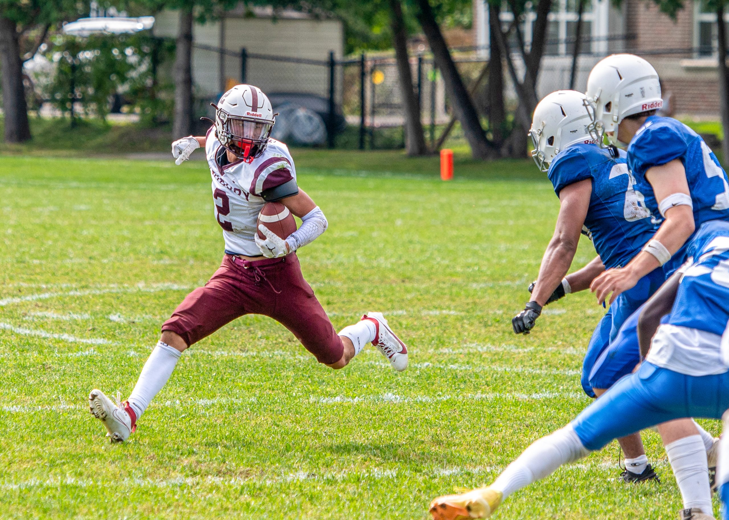 Man in a football uniform holding a football facing the opposing team