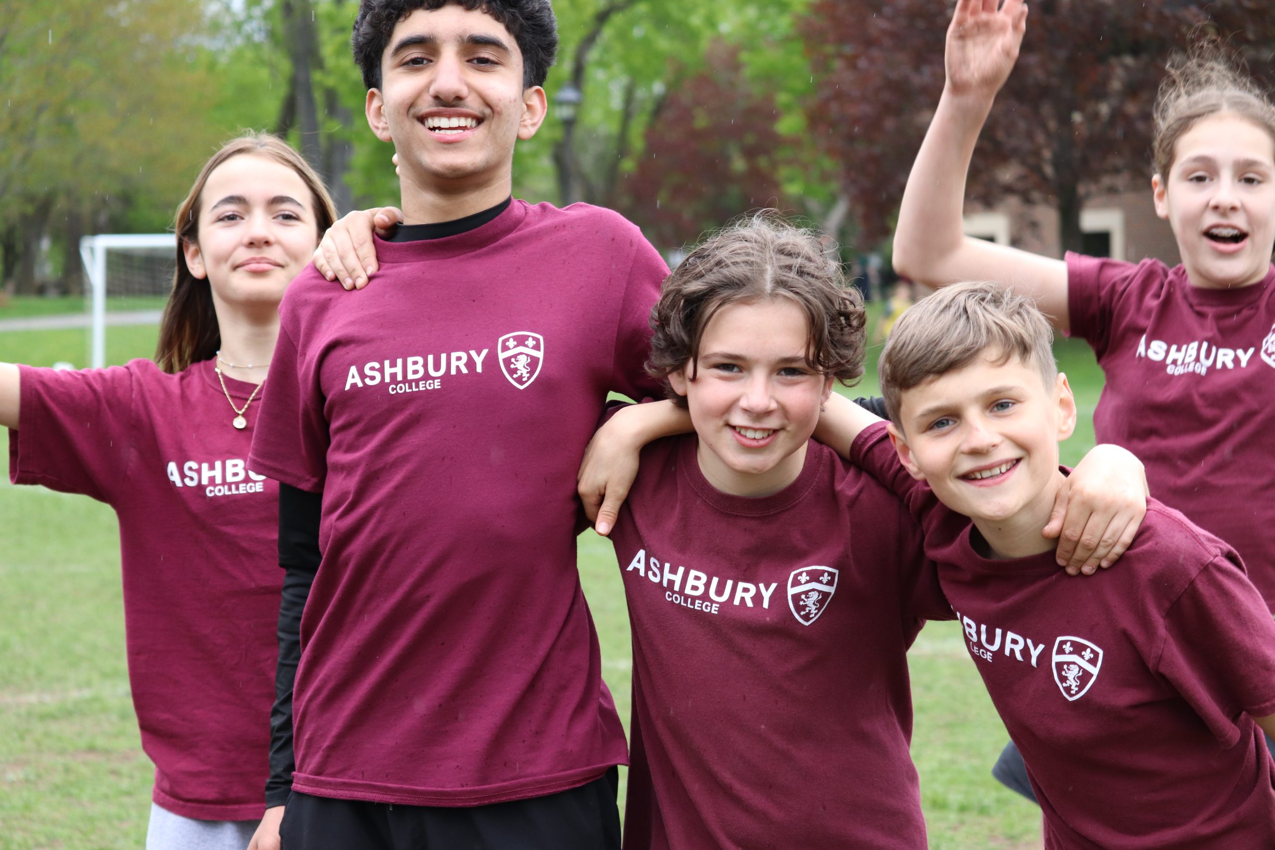 Group of young children smiling together in red Ashbury shirts
