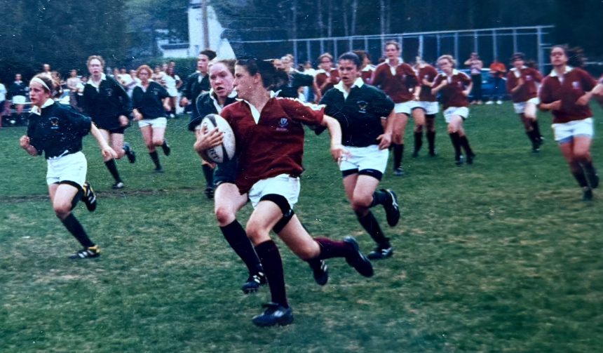 Julianne Zussman in her Ashbury uniform running away from opponents with a rugby ball in her hand